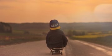 Journey to a wellbeing economy depicted by a boy on a skateboard in the middle of the road