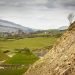 A photo of a Scottish landscape in Dumfries, Galloway, with green hills and fields and a large mound of earth close up. It is where there was once an open cast coal mine and has been transformed into an open space to be enjoyed by all.