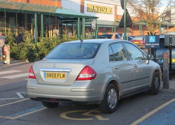 A photo of a Nissan Tilda parked on a supermarket car park on a disabled parking lot available for badge holders only. The image demonstrates the need for motability amongst disabled people.