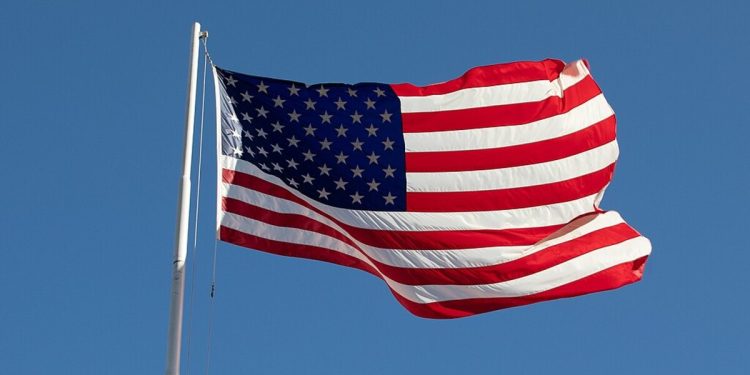 A photo of the American flag flying against a clear blue sky.