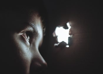 Palestinian child gazing through a bullet hole in a wall