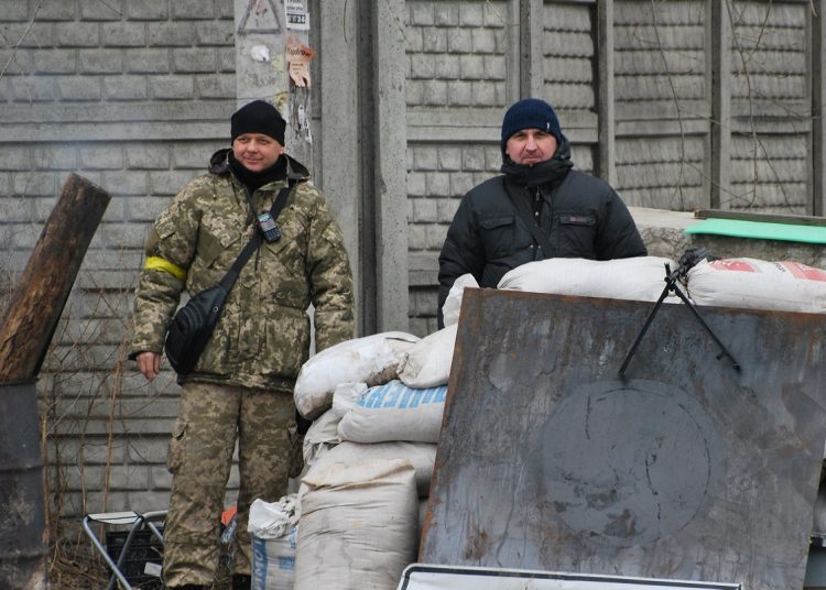 Two men stands at a point in the raod with sandbags for security